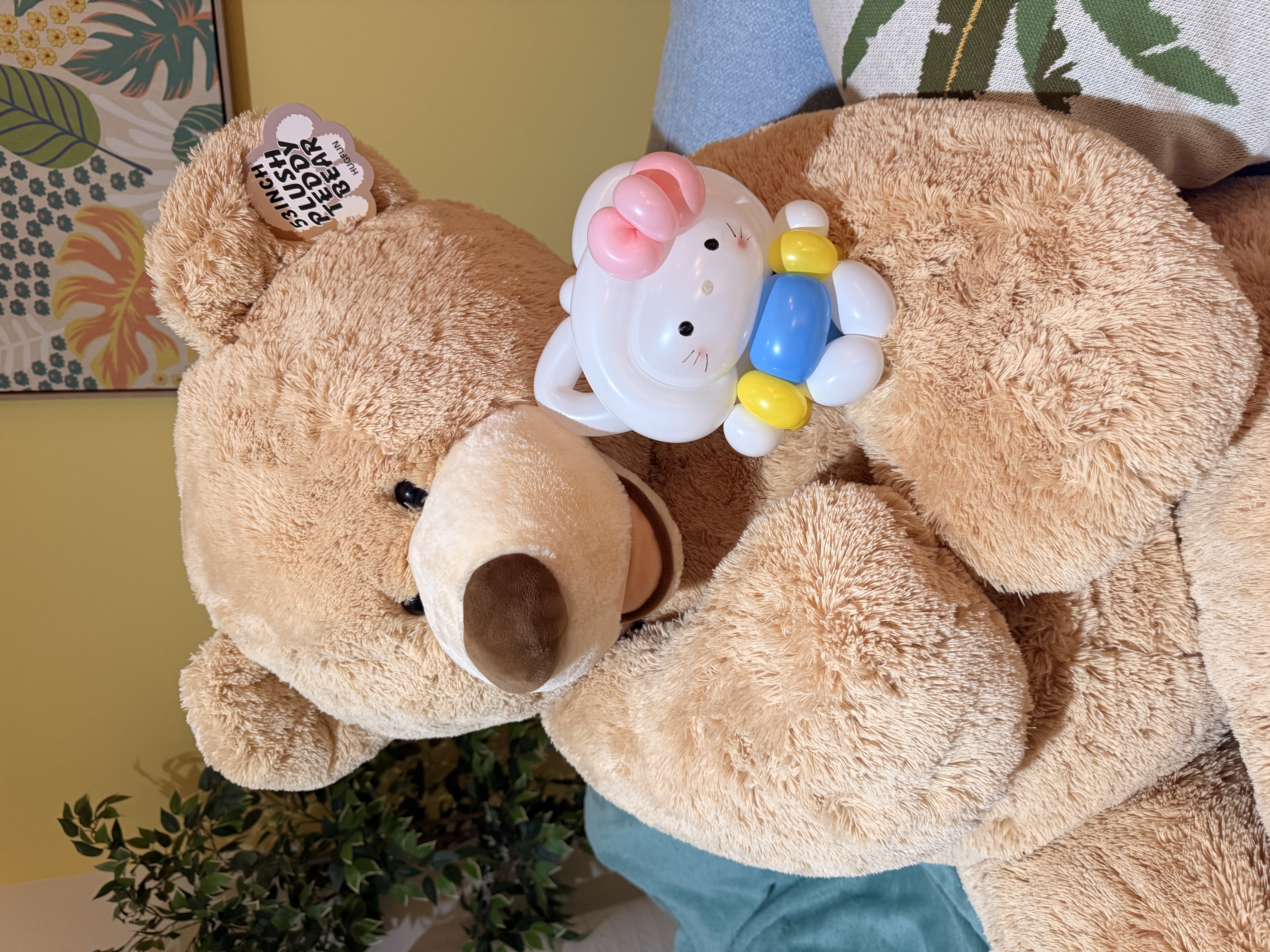 Hello Kitty balloon sitting on a large teddy bear