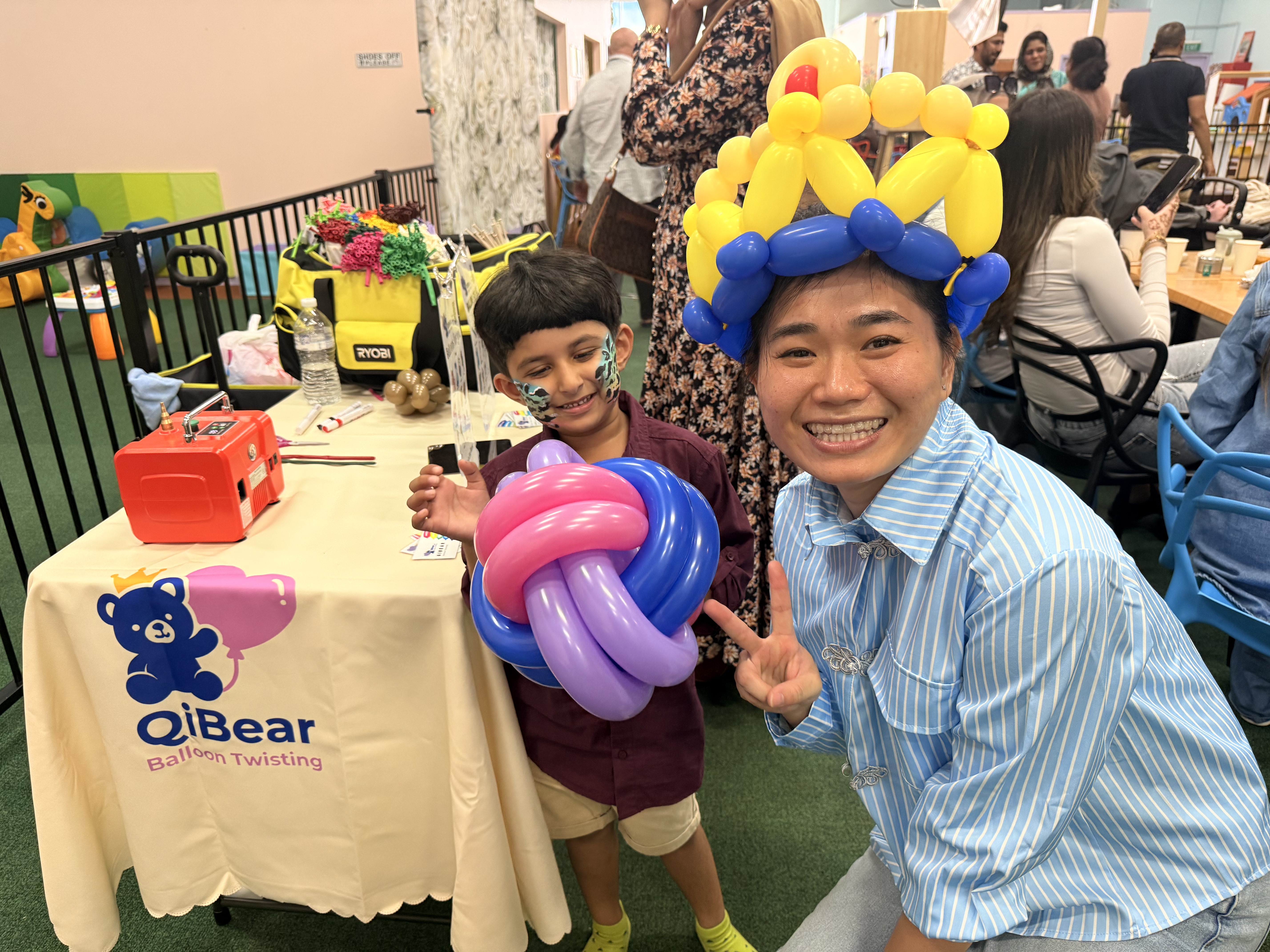 QiBear balloon artist twisting a balloon for a boy at an event