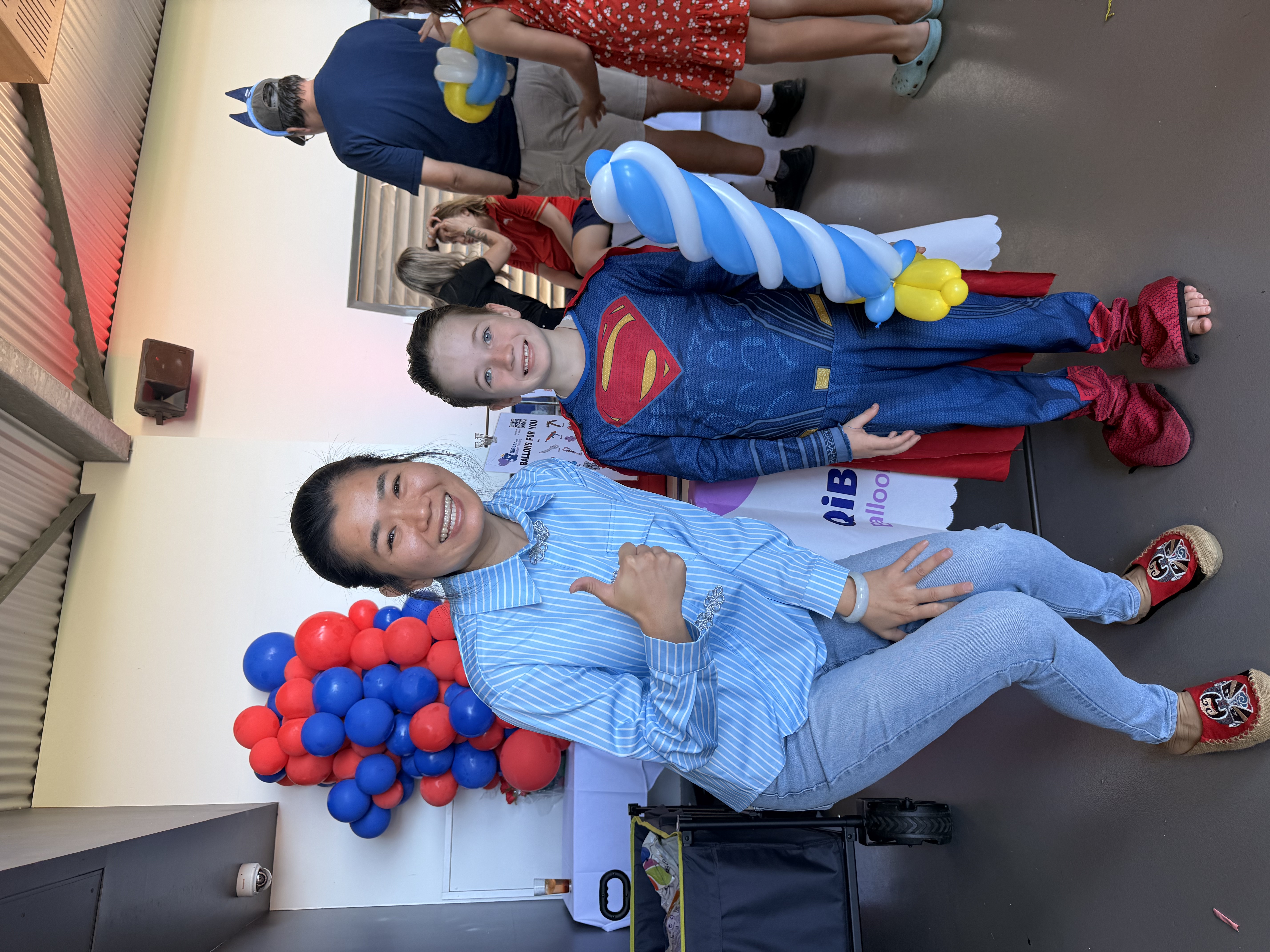 Balloon artist with boy wearing Superman costume and balloon