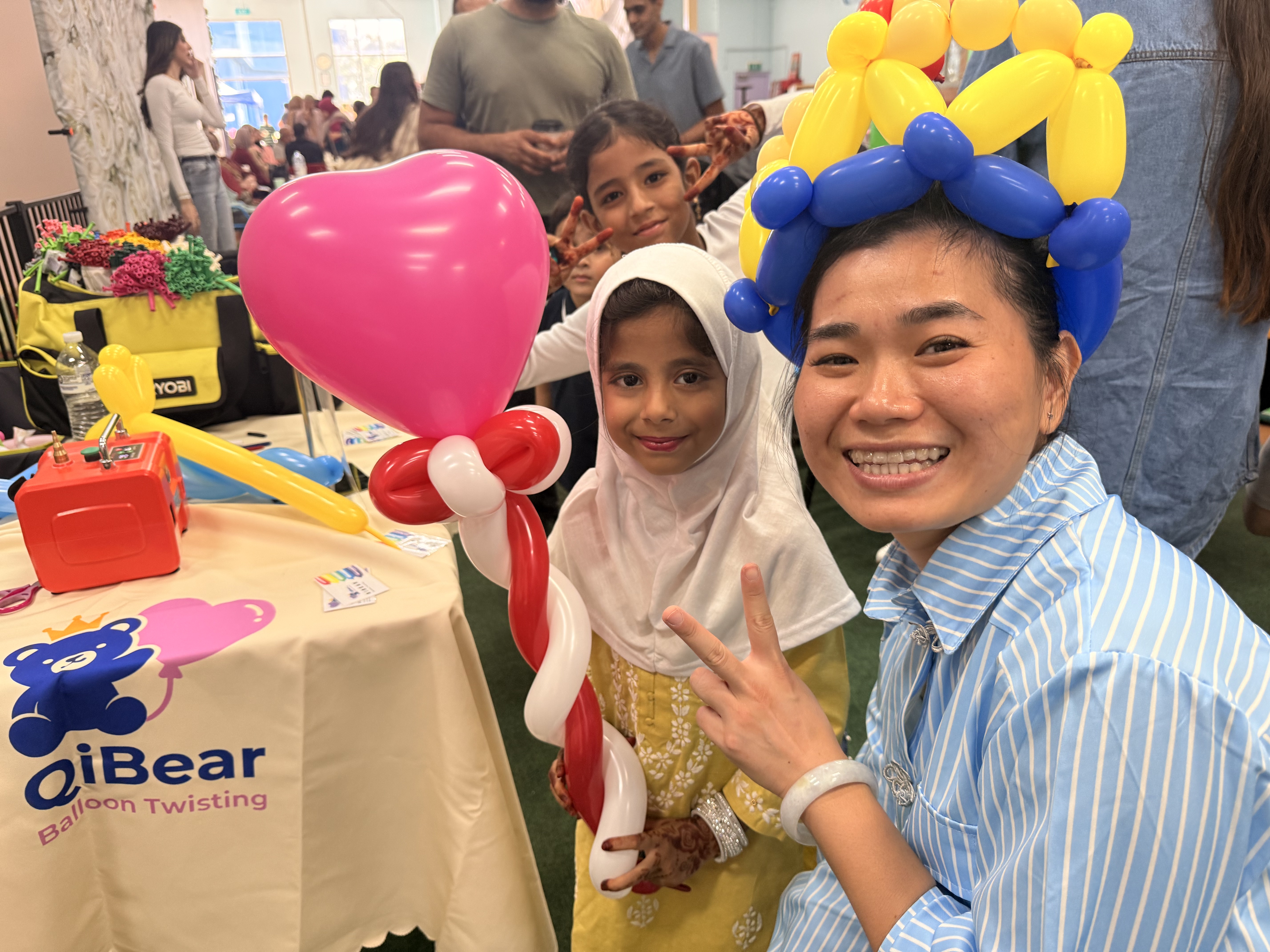 Balloon artist posing with girl holding heart balloon