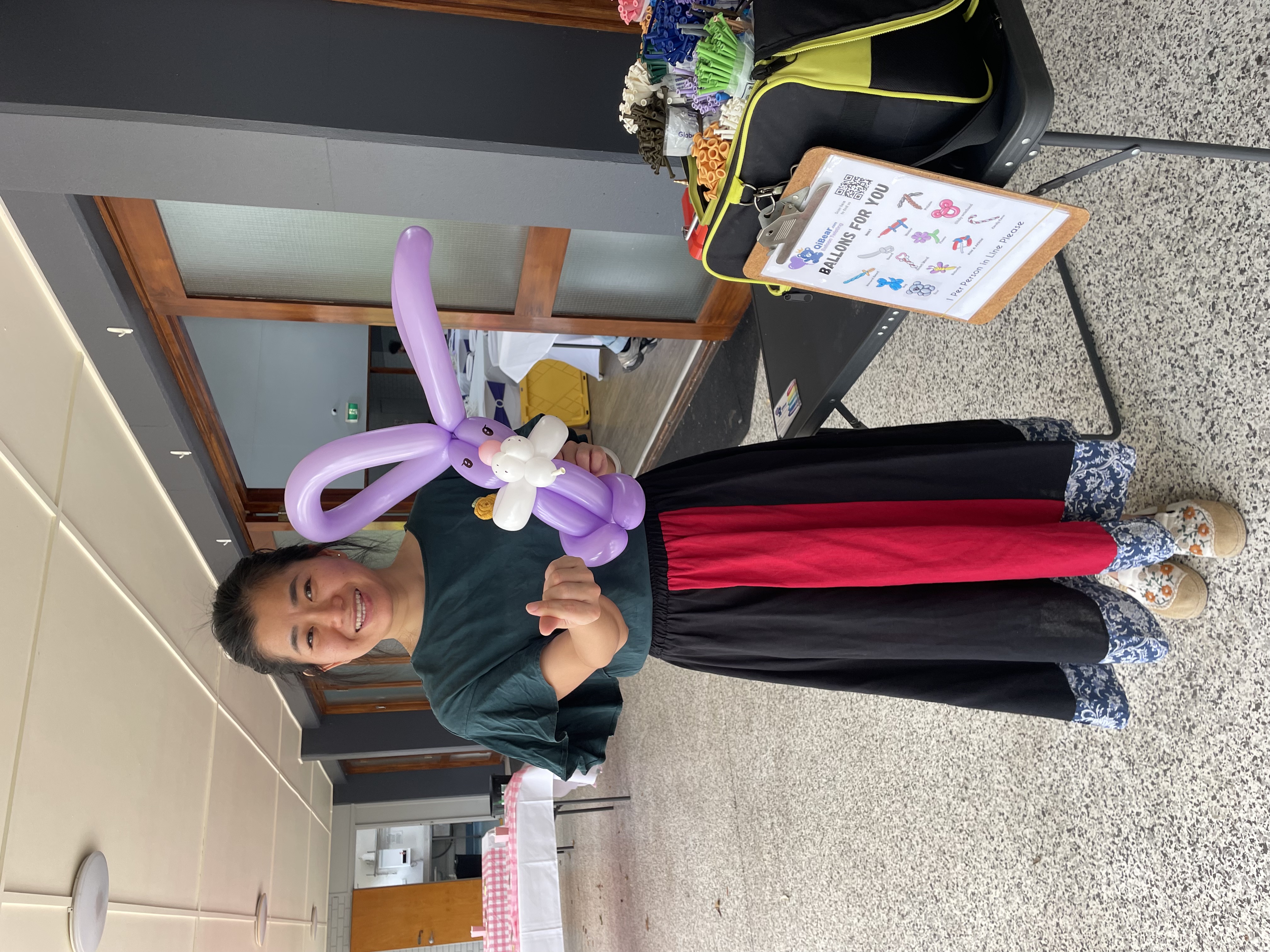 Balloon artist holding a purple rabbit balloon creation