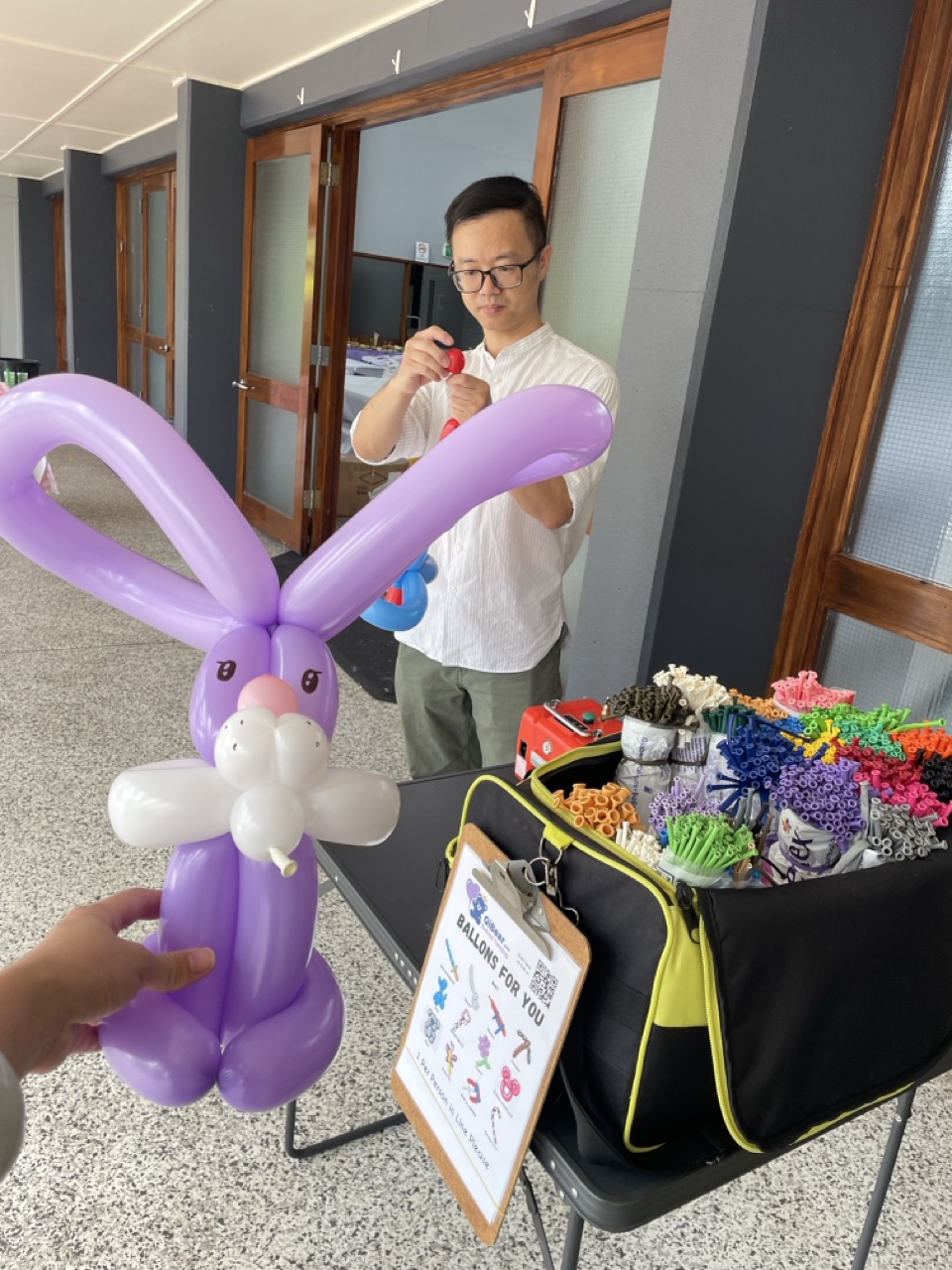 Balloon artist hand-crafting a purple rabbit balloon
